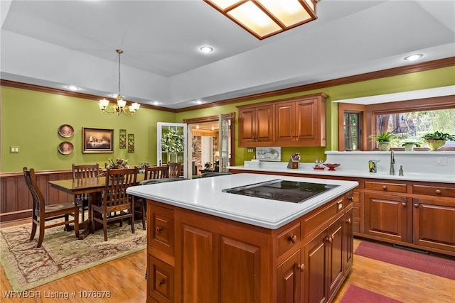 kitchen featuring a raised ceiling, a notable chandelier, pendant lighting, black electric cooktop, and a kitchen island