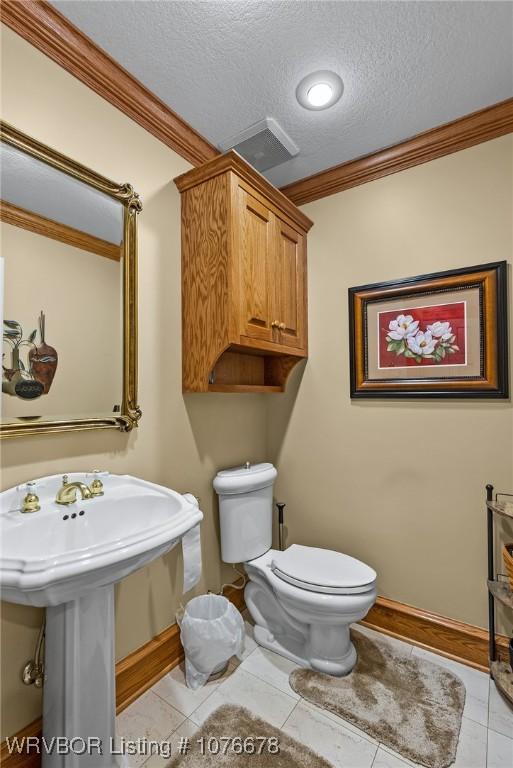 bathroom featuring tile patterned flooring, a textured ceiling, toilet, and crown molding