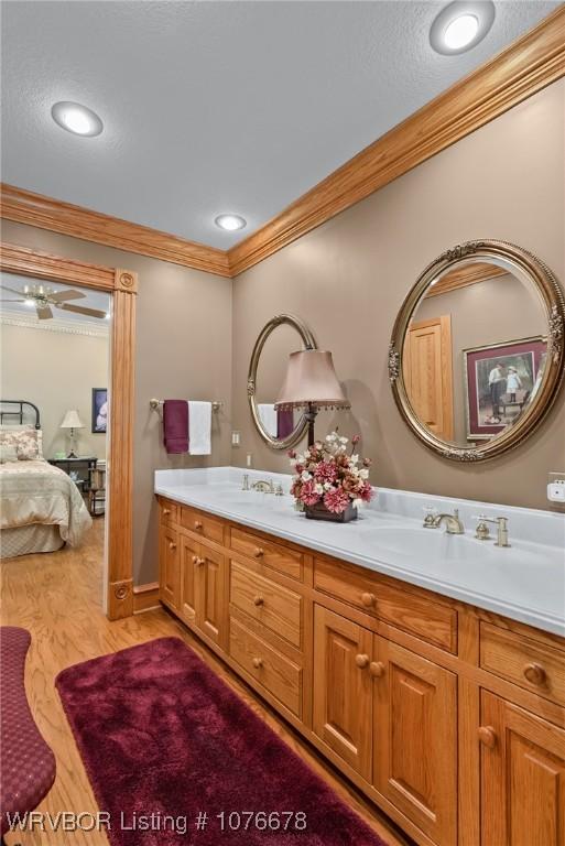 bathroom featuring vanity, ceiling fan, wood-type flooring, and ornamental molding