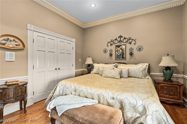 bedroom featuring hardwood / wood-style flooring, ornamental molding, and a closet