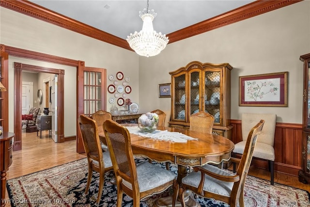 dining room featuring a chandelier, ornamental molding, and light hardwood / wood-style flooring