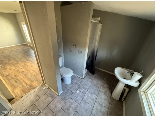 full bathroom with curtained shower, toilet, baseboards, and tile patterned flooring