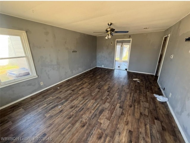 unfurnished room with baseboards, dark wood-type flooring, and ceiling fan