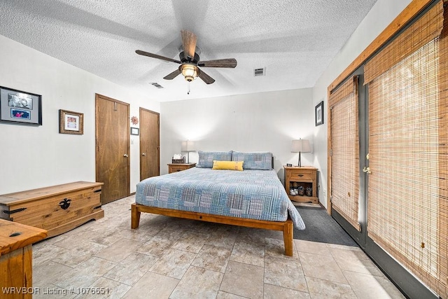 bedroom featuring two closets, a textured ceiling, and ceiling fan