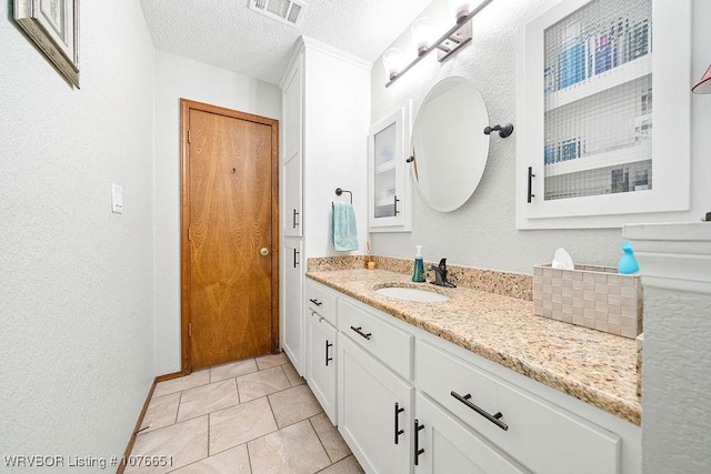 bathroom with tile patterned flooring, vanity, and a textured ceiling