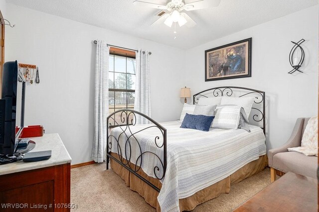 carpeted bedroom featuring ceiling fan and a textured ceiling