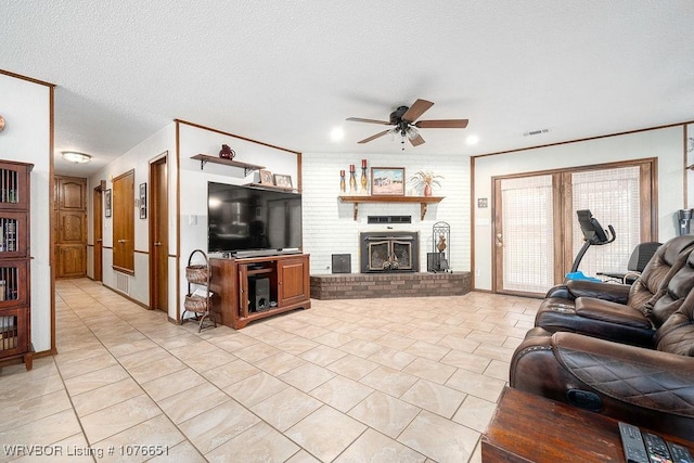 living room featuring light tile patterned flooring, ceiling fan, a fireplace, and a textured ceiling