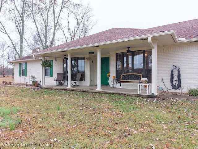 rear view of property featuring a yard and ceiling fan