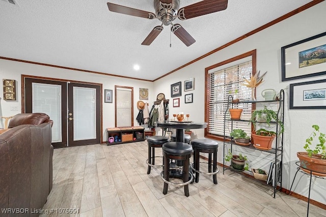 dining space featuring crown molding, ceiling fan, a textured ceiling, french doors, and light wood-type flooring