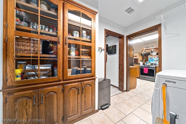 kitchen featuring washer / dryer, stainless steel electric stove, and light tile patterned flooring