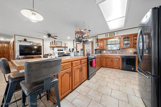 kitchen with sink, a textured ceiling, pendant lighting, ceiling fan, and black appliances