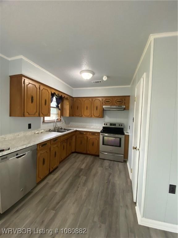 614 N School St, Charleston, AR 72933 - kitchen featuring appliances with stainless steel finishes, under cabinet range hood, a sink, light countertops, and dark wood-style floors