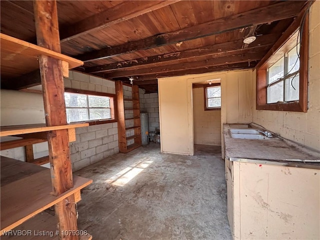 interior space with concrete block wall, water heater, and a sink