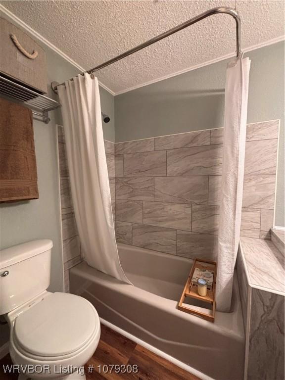 bathroom with a textured ceiling, toilet, wood finished floors, ornamental molding, and shower / tub combo with curtain