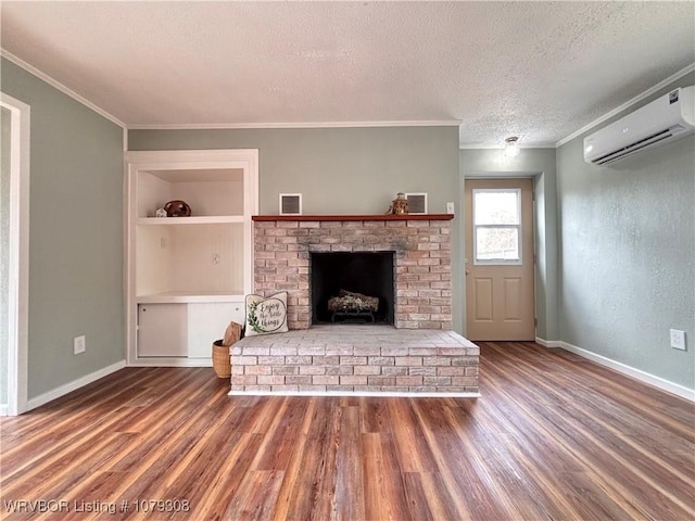 unfurnished living room featuring wood finished floors, a textured ceiling, an AC wall unit, built in shelves, and a fireplace