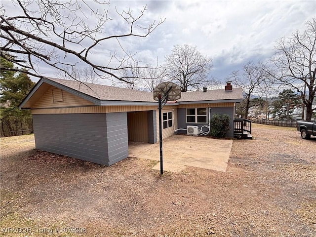 rear view of house featuring a patio area, a shingled roof, and a chimney