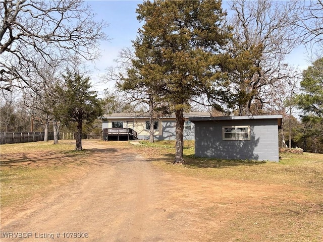 single story home with an outbuilding, concrete block siding, fence, driveway, and a wooden deck