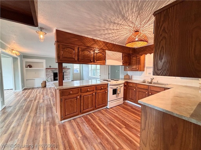 kitchen featuring electric range, a peninsula, extractor fan, a textured ceiling, and a sink