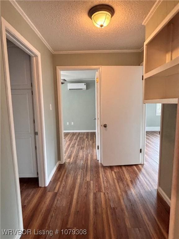 hallway featuring dark wood-style floors, a wall unit AC, crown molding, and a textured ceiling