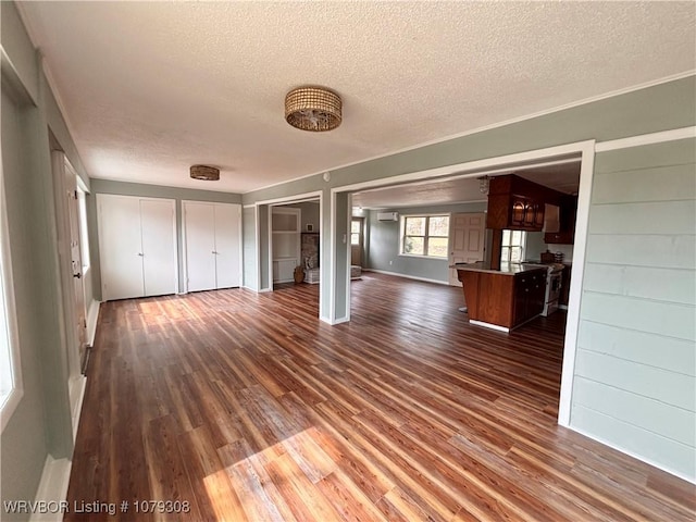 unfurnished living room with a textured ceiling, baseboards, and dark wood-style flooring