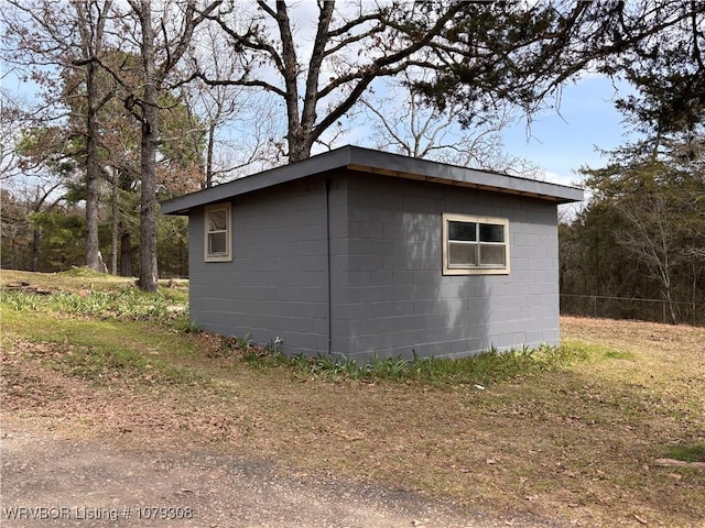 view of property exterior featuring concrete block siding and an outdoor structure