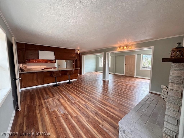 living room with ornamental molding, dark wood-style flooring, a textured ceiling, and baseboards