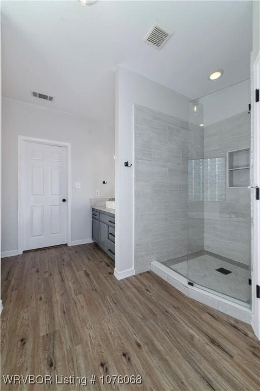 bathroom with vanity, wood-type flooring, and tiled shower