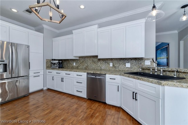 kitchen featuring decorative light fixtures, sink, white cabinetry, and stainless steel appliances