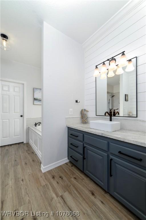 bathroom with hardwood / wood-style flooring, vanity, and a bathing tub