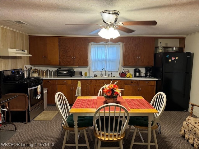 kitchen with ceiling fan, stainless steel gas stove, sink, a textured ceiling, and black refrigerator