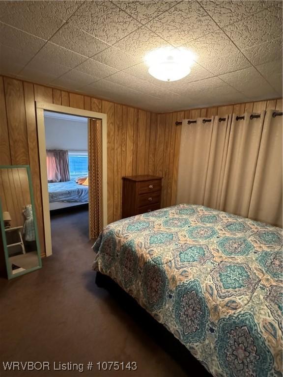 carpeted bedroom featuring wood walls