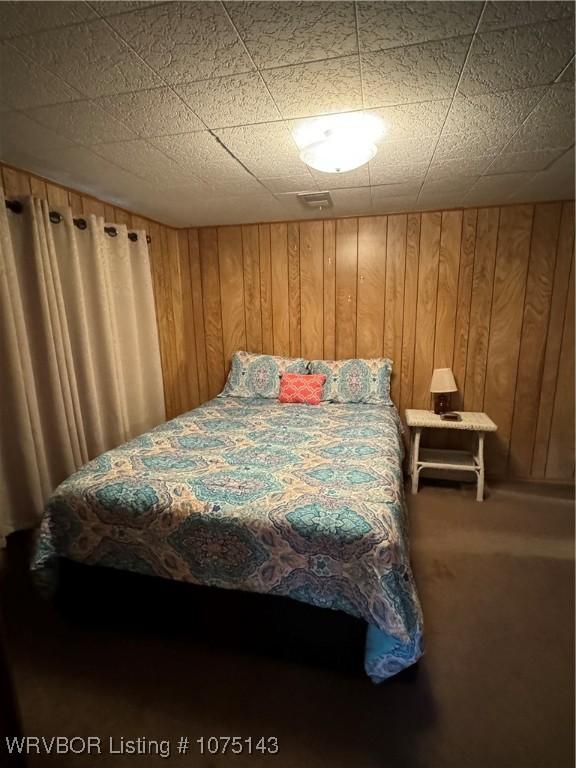 bedroom with carpet and wood walls