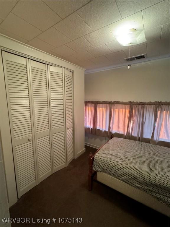 unfurnished bedroom featuring dark carpet, ornamental molding, and a closet