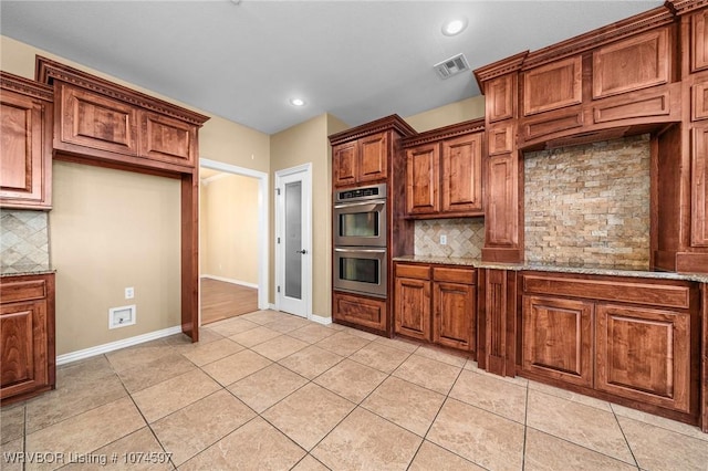 kitchen with light tile patterned floors, stainless steel double oven, tasteful backsplash, and light stone counters