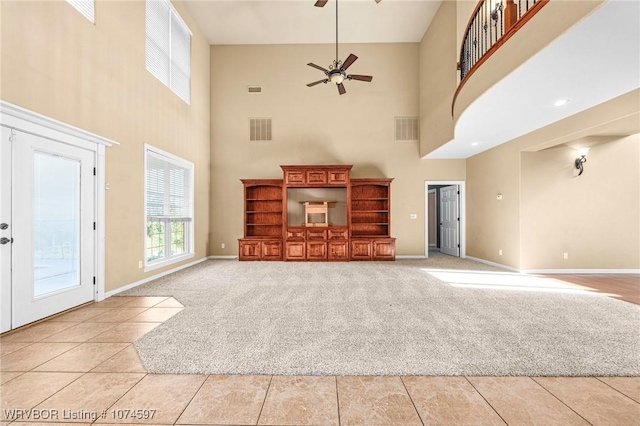 unfurnished living room with ceiling fan, light tile patterned floors, and a high ceiling