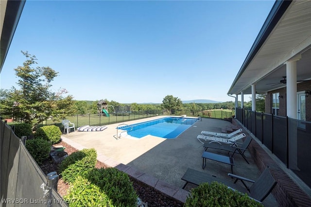 view of swimming pool with ceiling fan, a mountain view, and a patio