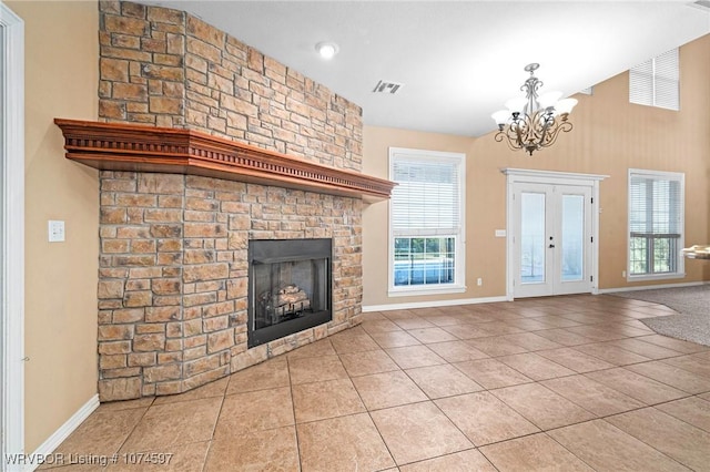 unfurnished living room featuring a healthy amount of sunlight, a large fireplace, light tile patterned floors, and a chandelier