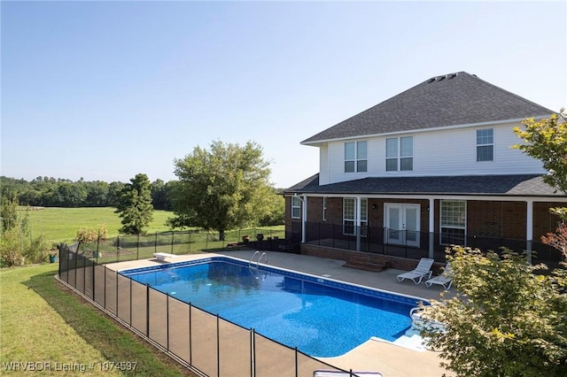 view of swimming pool with a yard, a diving board, french doors, and a patio