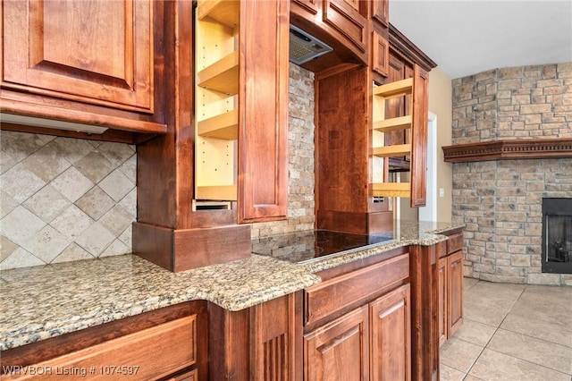 kitchen with light stone countertops, a fireplace, light tile patterned floors, and black electric cooktop