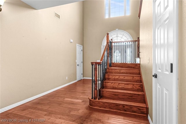 stairway with a high ceiling and hardwood / wood-style flooring