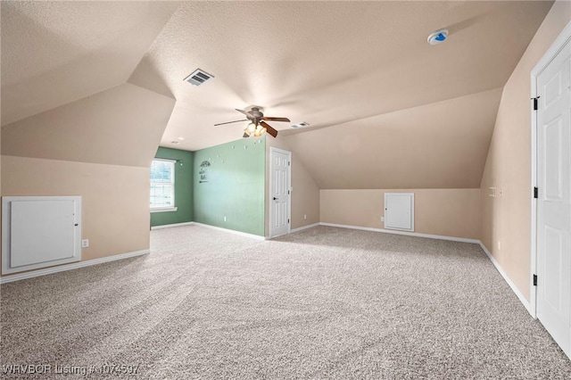 additional living space featuring lofted ceiling, ceiling fan, carpet floors, and a textured ceiling