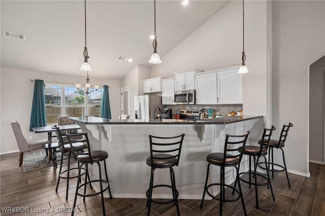 1138 Delta Dr, Van Buren, AR 72956 - kitchen with appliances with stainless steel finishes, white cabinets, dark wood-type flooring, decorative backsplash, and a breakfast bar