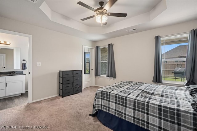 1138 Delta Dr, Van Buren, AR 72956 - bedroom featuring light carpet, a tray ceiling, connected bathroom, and a ceiling fan