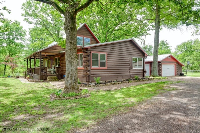 view of front of property featuring a garage, an outdoor structure, a front yard, and log exterior