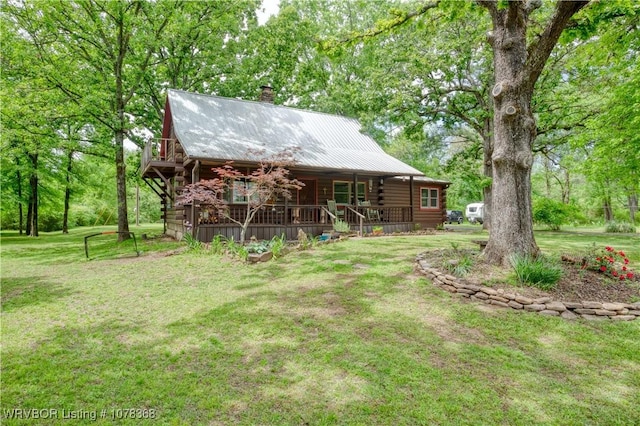 rear view of property with covered porch, a yard, a chimney, and log exterior
