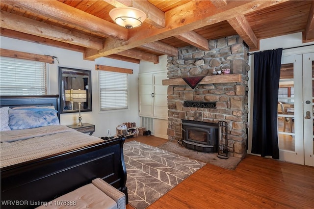 bedroom featuring hardwood / wood-style flooring, wooden ceiling, a wood stove, a closet, and beam ceiling