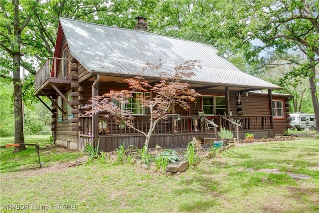 log home featuring a chimney, a porch, metal roof, log exterior, and a front yard