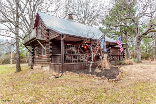 view of front of property featuring metal roof, log exterior, a chimney, and covered porch