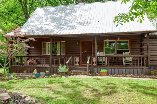 log-style house with metal roof, a porch, a front yard, and log exterior