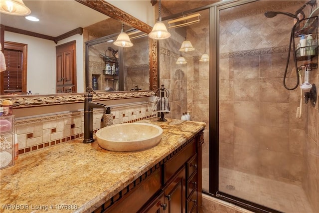 bathroom featuring an enclosed shower, vanity, tile walls, and ornamental molding